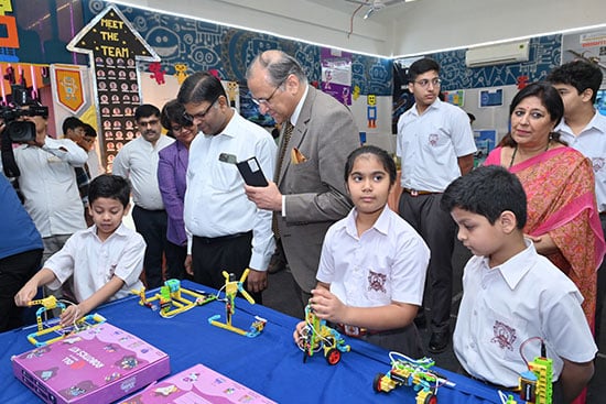 Students showcasing their robotics projects at an exhibition, with teachers and visitors observing