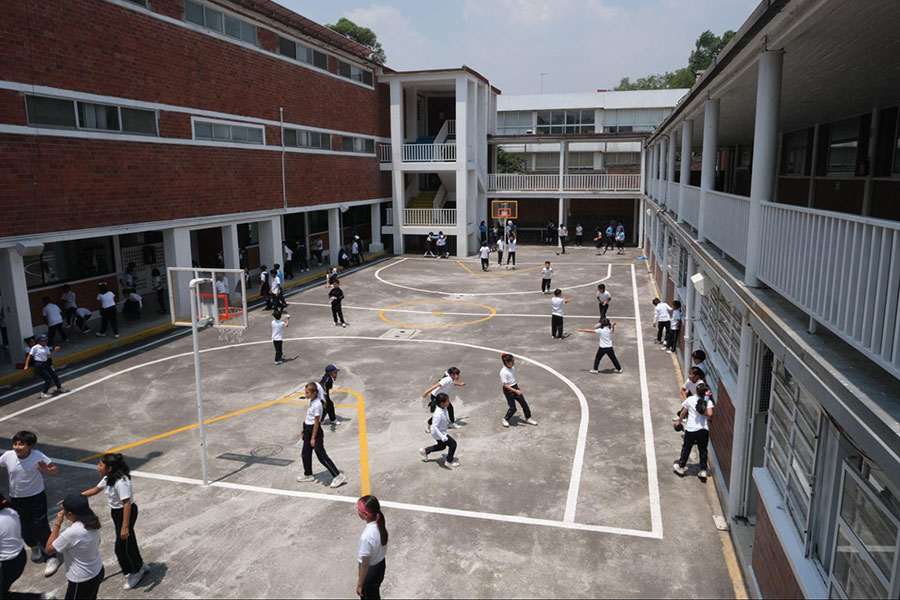 Students playing and interacting in a school courtyard during break time.
