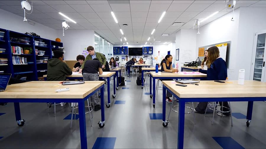 Students working on creative projects in a modern innovation lab with workbenches.