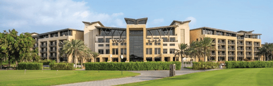 Vogo Hotel and Golf Club building with lush green landscape and palm trees.