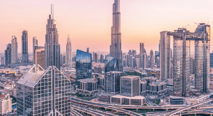 A panoramic view of the Dubai skyline featuring modern skyscrapers, the Burj Khalifa, and construction sites during sunset.