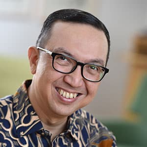 Smiling person wearing glasses and a patterned shirt