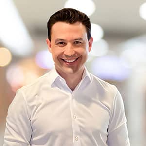 Smiling man in a white shirt standing in a modern office environment