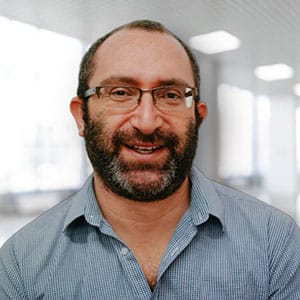 Smiling person with glasses and a beard in an office-like environment