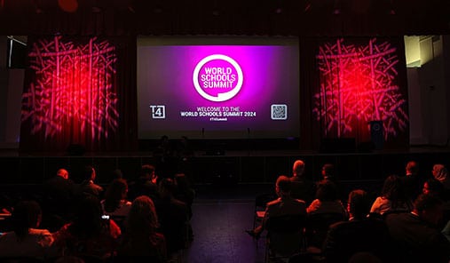 Audience seated in an auditorium at the World Schools Summit 2024 with a large stage screen displaying the event logo.