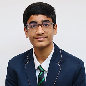 Smiling schoolboy wearing glasses and a navy school blazer with a striped tie