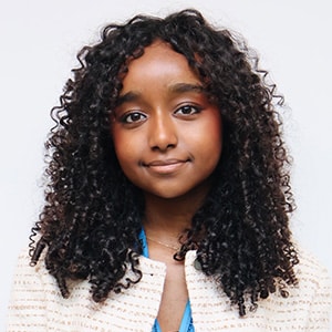 Smiling girl with curly hair wearing a light textured jacket
