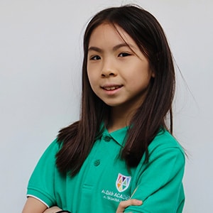 Smiling schoolgirl in a green polo school uniform with arms crossed