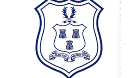 School crest with three tower symbols, laurel branch, and ribbon motto “Salvam Ole Libertate Peror”