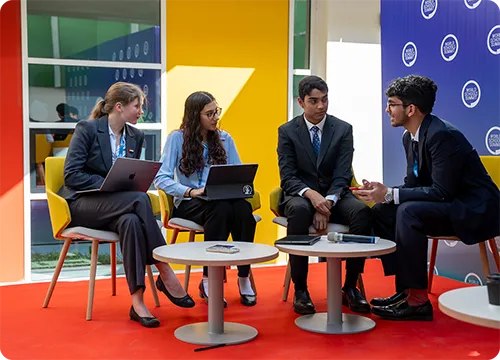Student Group Discussion and Collaboration at Conference Students in formal attire collaborating with laptops in a discussion area at an event