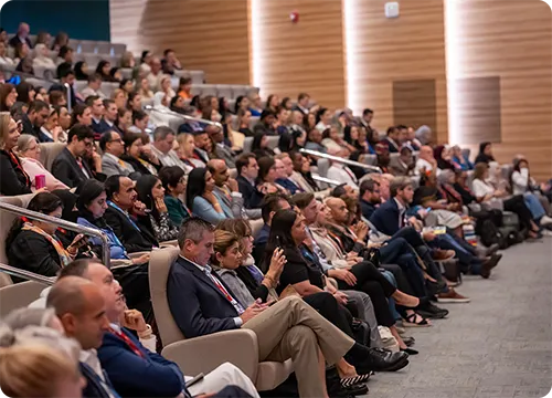 Conference Audience in Auditorium Listening to Speaker Audience seated in a large auditorium attending a conference session