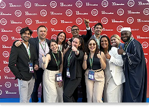 Conference Attendees Group Photo with Backdrop Group of diverse attendees posing together and smiling at a conference event