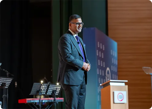 Conference Speaker Presenting on Stage Man in a suit speaking on stage at a conference event