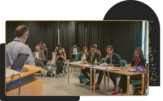 Speaker presenting to a seated panel and audience during a professional conference or workshop session