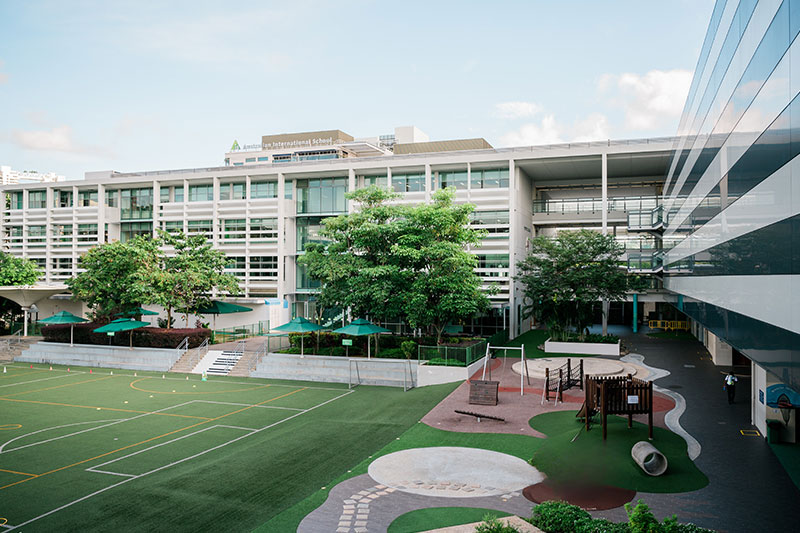 View of the Australian International School campus featuring modern educational facilities, outdoor play spaces, and sports areas.