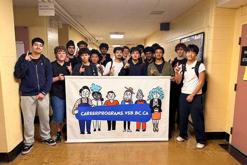 Secondary school students participating in Vancouver School Board Career Programs pose with a career pathways banner