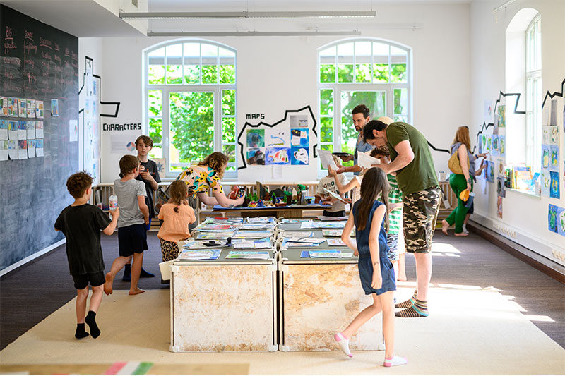 Students engaged in collaborative project-based learning activities within a creative classroom and exhibition space.