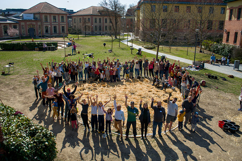 Students, families, and community members participating in a collaborative outdoor project focused on community engagement and sustainable development.