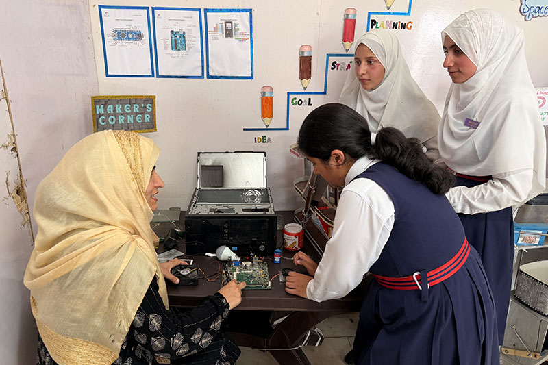 Students and educators collaborating on a computer hardware and electronics learning activity at Army Good Will School Wuzur