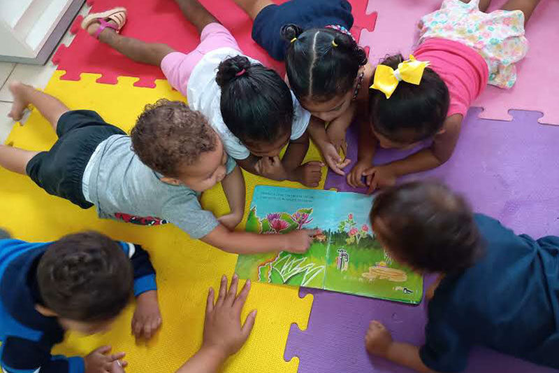 Young children gathered around a storybook during an early childhood literacy activity at a Fe y Alegría Brasil learning centre