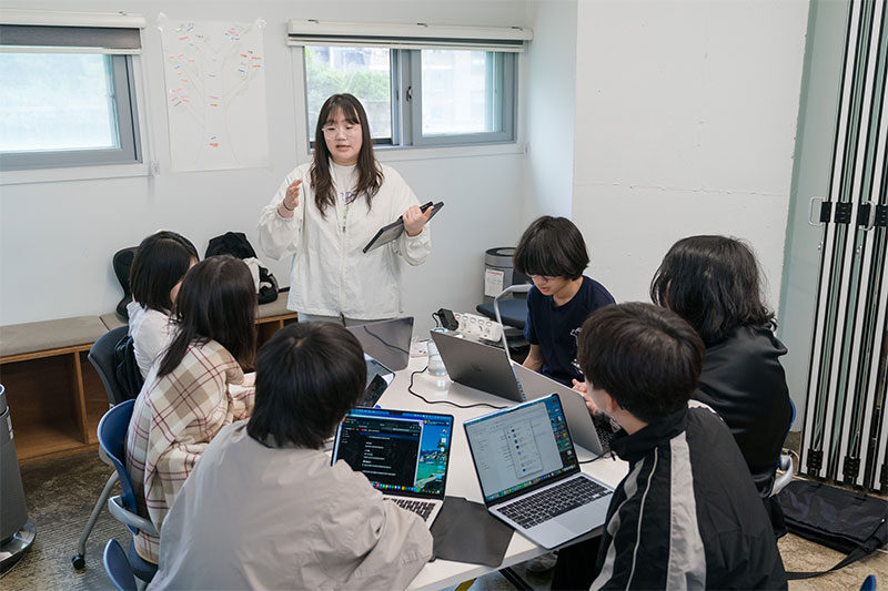 Students collaborating on digital projects and coding activities at a G-School technology learning workshop