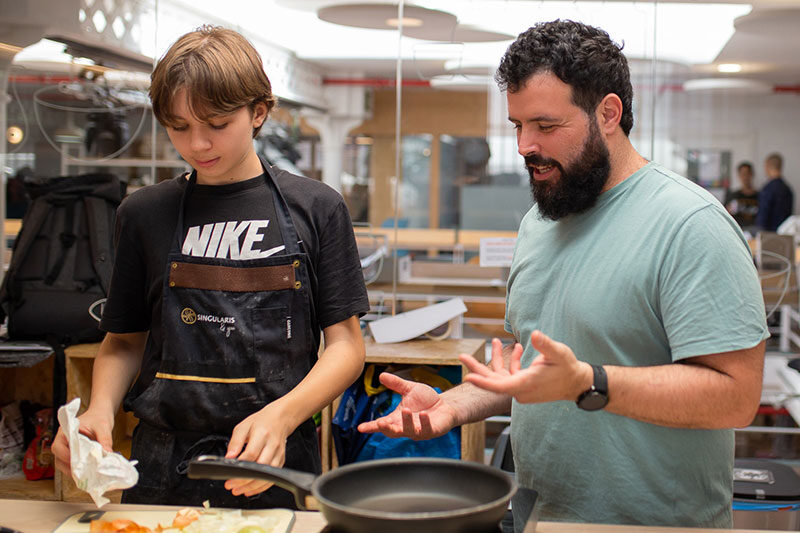 Learner preparing a meal with guidance from a mentor during a practical life skills programme at Learnlife