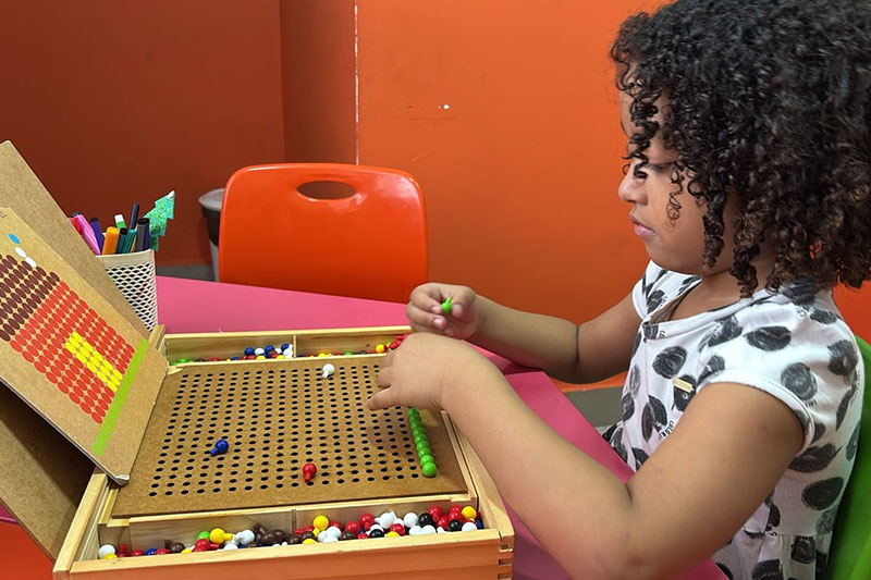 Student using hands-on learning materials to develop numeracy and problem-solving skills at Primeiro Mundo