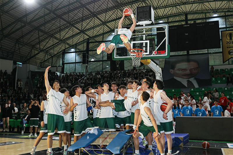 Darüşşafaka students participating in a basketball showcase featuring athletic skills and teamwork in a packed arena