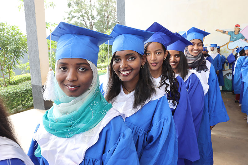 Graduating students in blue academic gowns celebrating their achievement at a Pharo Foundation supported school