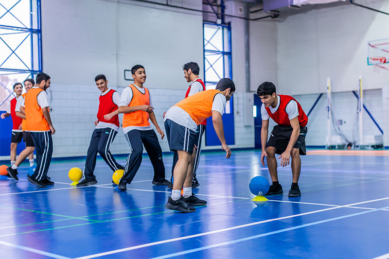 Students participating in indoor sports and teamwork activities as part of a balanced educational experience