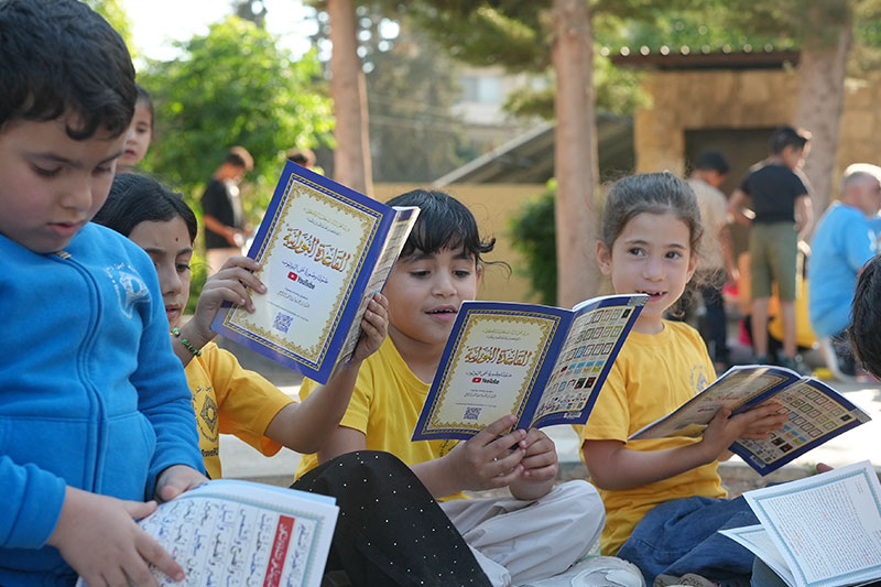 Students participating in outdoor religious and cultural studies while reading educational materials at Ibn Rushd National Academy