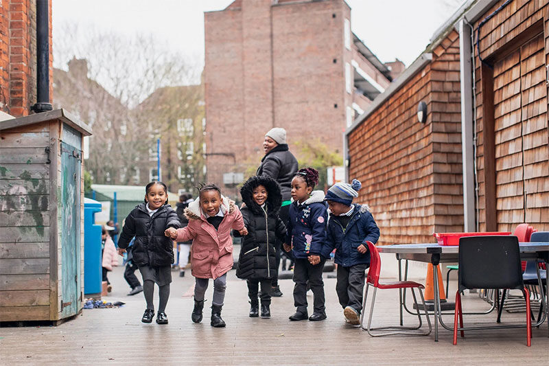 Young students running and playing together in an outdoor learning and recreation area at SSQ School