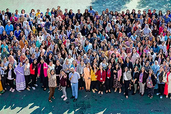 Large group of educators and school staff posing together for a group photo outdoors.