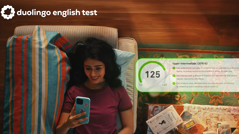 Woman using her smartphone to view a Duolingo English Test score of 125, corresponding to CEFR B2 Upper Intermediate English proficiency.